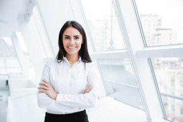 Smiling Business woman near the window with arms crossed