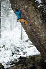 Outdoor winter sport. Rock climber ascending a challenging cliff. Extreme sport climbing. 