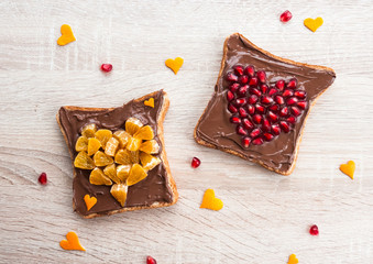 Chocolate sandwich with pomegranate heart and tangerine heart - creative idea for healthy kids breakfast, dessert or holiday meal for Valentines day, top view flat lay