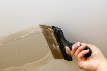 hand of worker using gypsum plaster ceiling joints at construction site