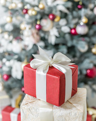 Red gift box and decorated New Year Tree on the background.