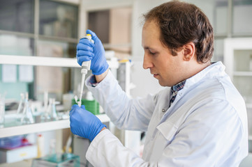 Scientist in the laboratory filling test tubes with pipette