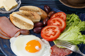 Substantial breakfast with fried egg, salad, bacon, bread and coffee