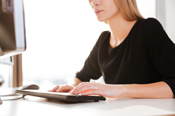Cropped image of young woman worker typing by keyboard.