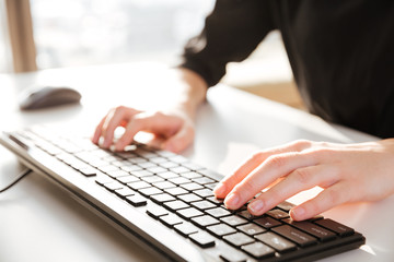 Cropped photo of young woman worker typing by keyboard.