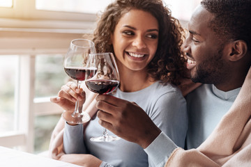 Positive African American couple holding wineglasses in the restaurant