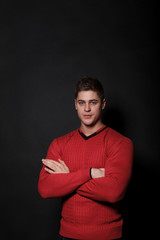 Lovely man standing on a black background. Very handsome man dressed in a red sweater.