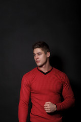 Naklejka premium Lovely man standing on a black background. Very handsome man dressed in a red sweater.