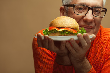 Fabulous at any age, vegetarian food concept. Portrait of fashionable man with burger