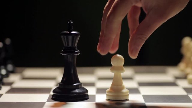 Panning shot of a chess board, with white pawn conquering the black king.