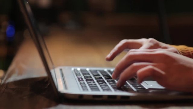 Moving shot of a woman's hands working on a laptop.