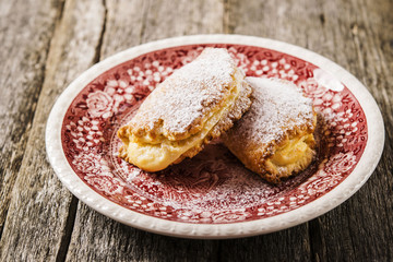 Traditional Russian sweet pies of short pastry with curd sprinkled with powdered sugar on a bright painted plate on a dark shabby wooden background. Selective focus 