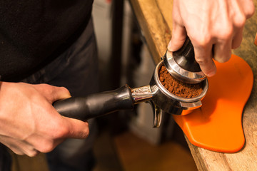 Barista presses ground coffee using tamper.