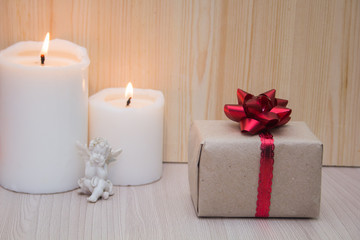 Gift boxes with red bow, white candles and a statuette of an angel. Concept for 14 February, romantic anniversary.