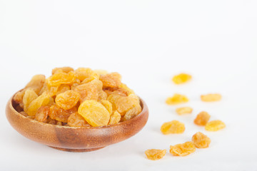 Yellow raisins or sultanas in a small wooden bowl on white background