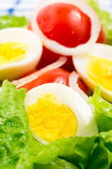 Boiled eggs and cherry tomatoes in a salad with lettuce leaves