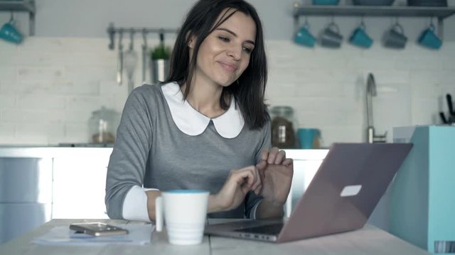 Businesswoman finishing working on laptop and drinking coffee by table in office
