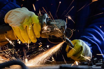 Man cutting steel pipe with an angle grinder producing hot sparks