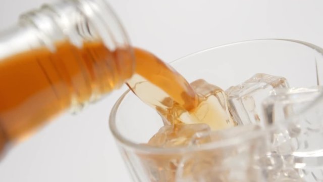 SLOW MOTION: Whiskey pour in a glass with an ice cubes from a bottle - close up