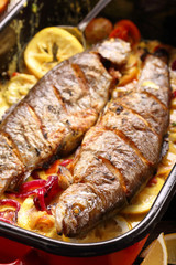 Baked fish with lemon sauce and vegetables in a pan