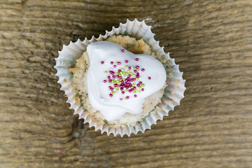 Top down view on cupcake with candies and frosting over old wooden surface background