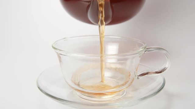 SLOW MOTION: Human pours a tea in a cup from a teapot - close up