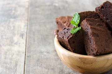 Chocolate brownie portions in bowl on wooden background
