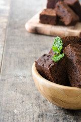 Chocolate brownie portions in bowl on wooden background
