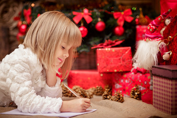 Obraz na płótnie Canvas little girl writes a letter to Santa Claus