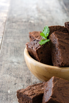 Chocolate brownie portions in bowl on wooden background
