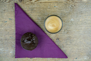 Overhead view of coffee with chocolate cake and napkin on wood table with copy space
