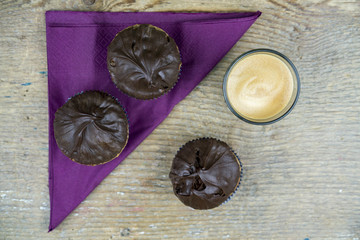Overhead view of chocolate cakes, coffee and napkin on wooden table