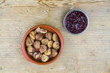 Overhead view of sweet chestnuts with cranberry sauce on rustic wooden table
