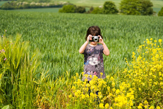 Little Girl taking a picture and enjoying photography in the beautiful rural landscapes of Warwickshire, England.
