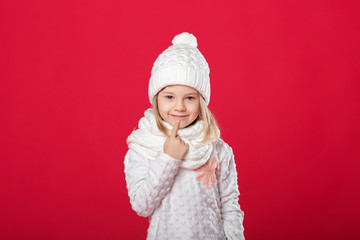 little smiling blonde girl in a white hat and scarf on red backg