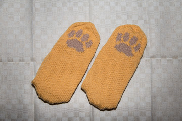 Pair of a hand knitted woolen socks with a cat paw pattern on linen background