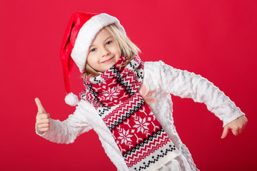 little girl in santa hat and scarf on red background