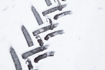 Tractor tire imprint in the wet, soft snow on the asphalt in winter day. Slippery road. Background.