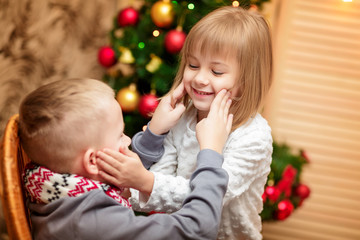 two small children in the background of the Christmas tree