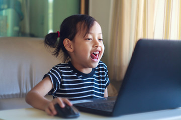 Cute child smiling and playing laptop at home with happy.Selecti