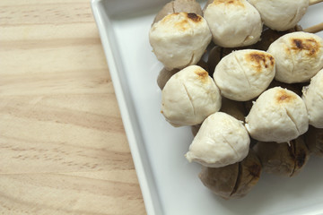 Pork meatballs on white plate placed on a wooden floor.