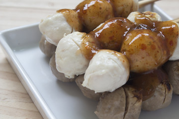 Pork meatballs on white plate placed on a wooden floor.