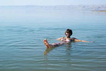 Mud covered female floats in the Dead Sea
