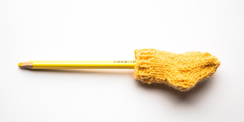 A small, hand knitted woolen sock with a color pencil on light background