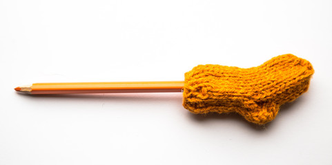 A small, hand knitted woolen sock with a color pencil on light background