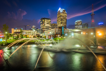 Fototapeta na wymiar Fountains and the Charlotte skyline at First Ward Park at night,