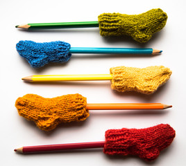 Small, hand knitted woolen socks with a color pencils on light background