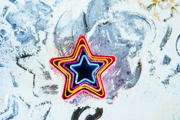 Fototapeta premium Making cookies as christmas gift, sugar powder and cookies cutter and cooking tools photographed from above on a dark and wooden background