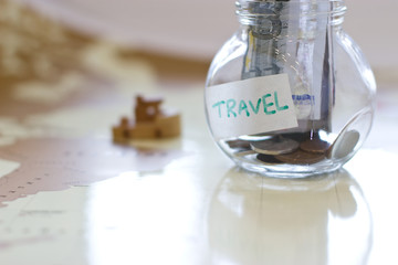 Obraz na płótnie Canvas Travel budget - vacation money savings in a glass jar on world m