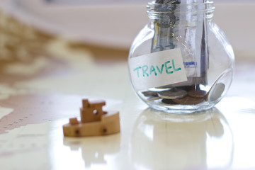 Travel budget - vacation money savings in a glass jar on world m